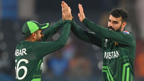 Pakistan players Babar Azam (left) and Shadab Khan (right) celebrate a wicket