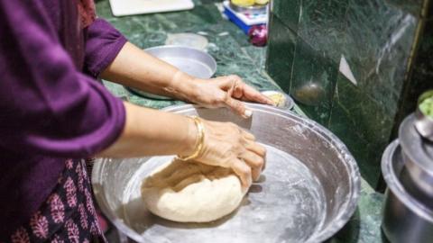 A woman prepares dough for traditional Indian bread chapati in the kitchen at Boisahabi Tea Estate, Assam, India on 7 March, 2019.