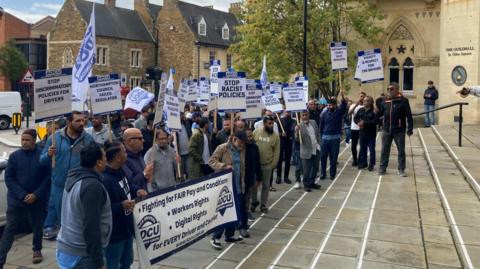 Drivers carrying banners on the steps of a large municipal building