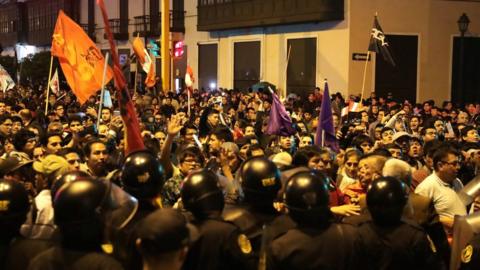 Police keep watch as supporters of Peru's President Martin Vizcarra celebrate outside the Congress building