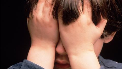 Child with his hands over his face