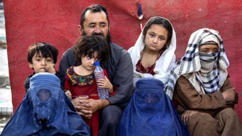 Charyar,70, from the Balkh province sits alongside his family at a makeshift IDP camp in Share-e-Naw park