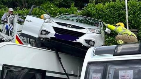 A car stuck on top of two caravans