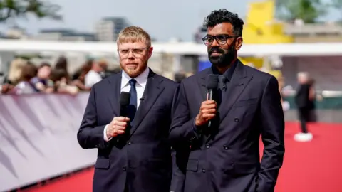 Rob Beckett and Romesh Ranganathan holding microphones on the red carpet of the Bafta TV Awards in 2023