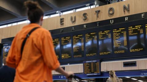 Woman at London Euston train station departures board