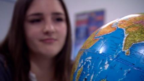 A school girl looks at a globe