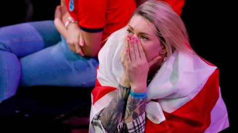 A woman wearing an English flag watches the game