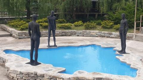 Three figures urinate in a pool shaped like Bosnia and Hercegovina