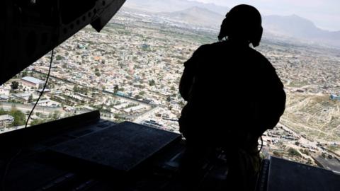 A U.S. soldier mans a gun at the back gate aboard the helicopter