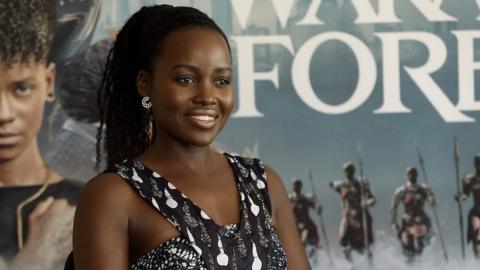 Lupita Nyong’o in front of Black Panther; Wakanda Forever poster