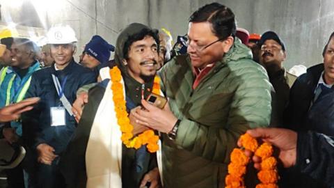 UTTARAKHAND, INDIA - NOVEMBER 28: (----EDITORIAL USE ONLY MANDATORY CREDIT - 'TURKISH AGRICULTURE AND FORESTRY MINISTRY / HANDOUT' - NO MARKETING NO ADVERTISING CAMPAIGNS - DISTRIBUTED AS A SERVICE TO CLIENTS----) Uttarakhand Chief Minister Pushkar Singh Dhami (C) with the rescued worker inside the tunnel on the Brahmakal Yamunotri National Highway in Uttarkashi, India, 28 November 2023. Uttarakhand Chief Minister Pushkar Singh Dhami said that the laying of pipes through the rubble was completed and all of the 41 trapped workers will be evacuated soon. 41 workers became trapped after an under-construction tunnel collapsed on 12 November. (Photo by UTTARAKHAND INFORMATION DEPARTMENT/Anadolu via Getty Images)