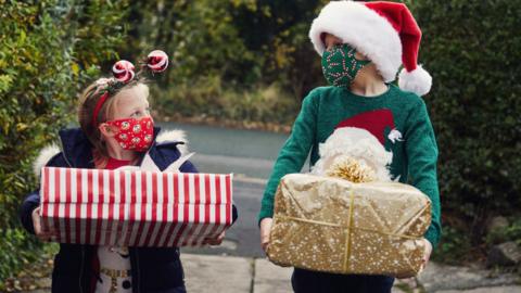 Two Children carrying Christmas presents - stock photo