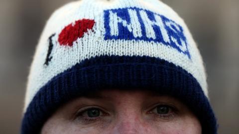 Woman wearing knitted "I love NHS" hat