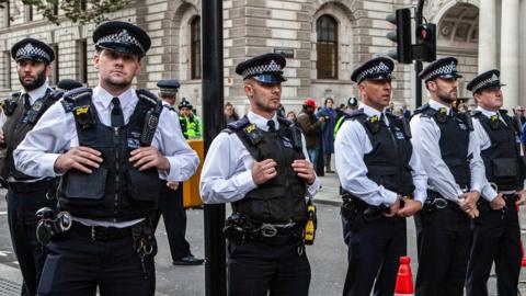 Police officers standing in a row in the middle of a road