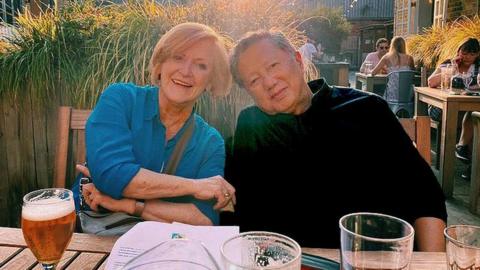 Safiah's mum Barbara sitting next to Safiah's dad, Zahari, at an outdoor restaurant.