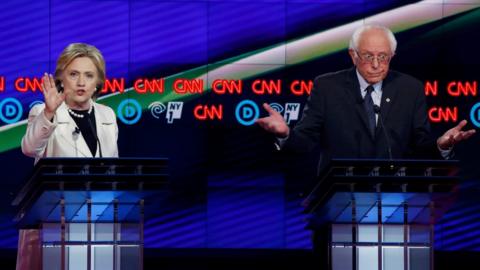 Democratic U.S. presidential candidate Hillary Clinton (L) speaks as Senator Bernie Sanders reacts during a Democratic debate hosted by CNN and New York One at the Brooklyn Navy Yard in New York April 14, 2016.