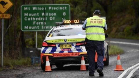 A police officer and vehicle set up a roadblock in the Blue Mountains near Sydney