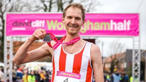 Male runner holding medal