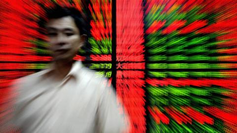 A Chinese investor walks past an electronic board showing stock index figures at a trading house in Shanghai on September 16, 2009.