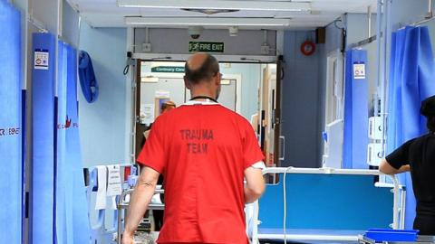 Medic in orange scrubs walks through ward