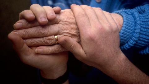 Health carer holds the hand of an elderly patient