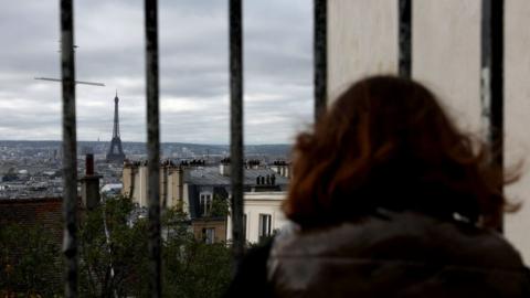 A woman looks out at Eiffel Tower on November 03, 2023 in Paris, France. Paris will host the Summer Olympics from July 26 till August 11, 2024