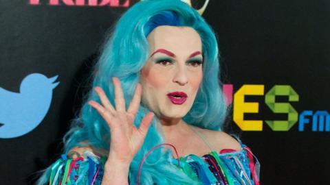 Spanish singer Amapola Lopez - known as 'La Prohibida' - waves for the cameras in a blue dress that matches her blue hair