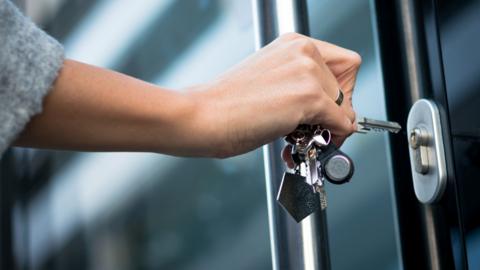 A woman opening house door with keys