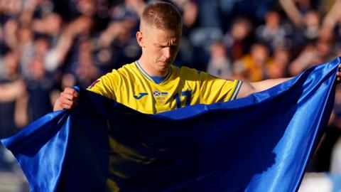 Oleksandr Zinchenko displays the Ukraine flag on the pitch against Scotland