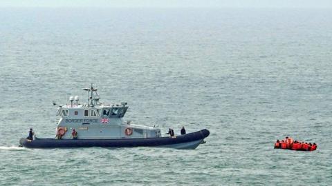 Border Force vessel in the English Channel with a small boat carrying people in life jackets