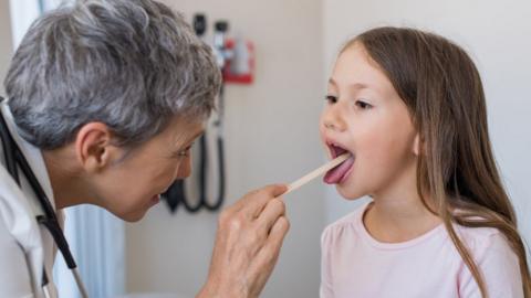 Doctor checking child's tonsils