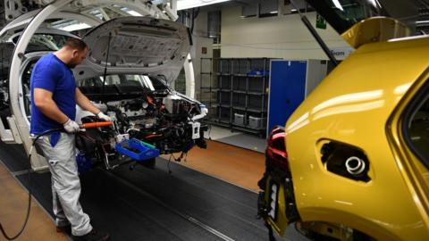 A worker assembles a power electronics device for a Volkswagen Golf