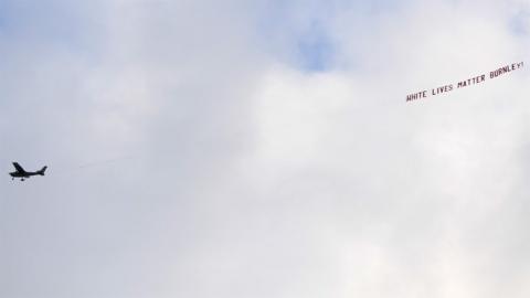 A plane flies over the stadium with a banner reading "White Lives Matter Burnley"