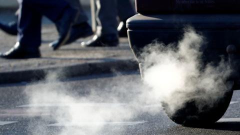 An exhaust pipe of a car is pictured on a street in Berlin, Germany