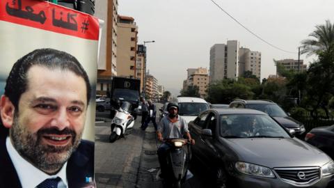 Cars pass next to a poster showing Saad Hariri and saying "All of us are with you" in Beirut, Lebanon (13 November 2017)