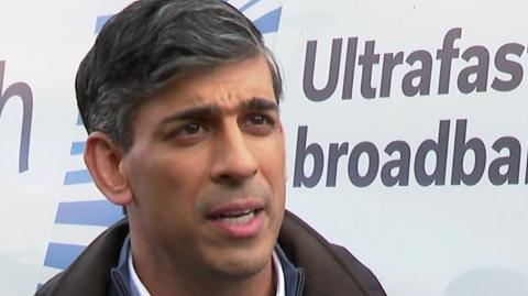 Rishi Sunak stands in front of a white van