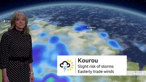 Louise Lear stands in front of a weather map showing the Kourou launch site in French Guiana