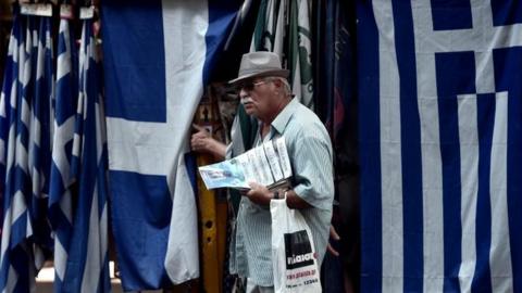 Man standing in front of Greek flags