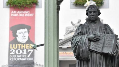 A statue of German Church reformer Martin Luther alongside a poster in the main square in Wittenberg, eastern Germany, 31 October 2017