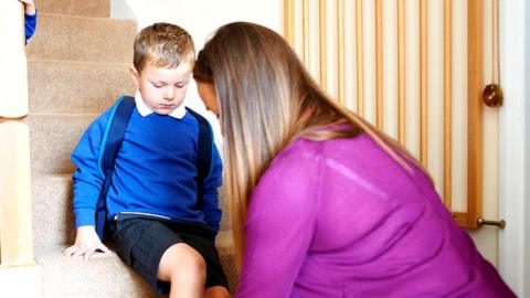 A stock image of a mother helping her children get ready for school