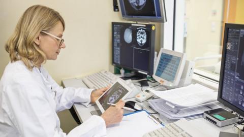 A radiologist looking at scans on a screen