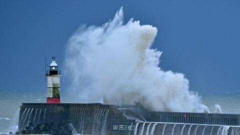 Waves crash over Newhaven Lighthouse on the south coast of England on 27 December