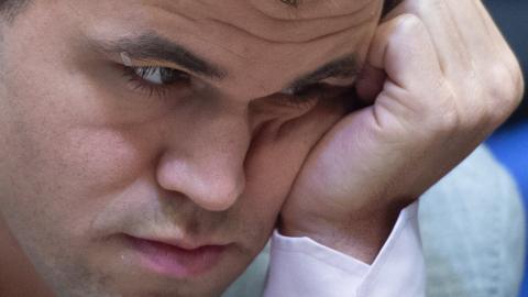 Magnus Carlsen is seen in extreme close-up, hand resting on his cheek and staring intensely - perhaps even apprehensively - at the game board out of frame