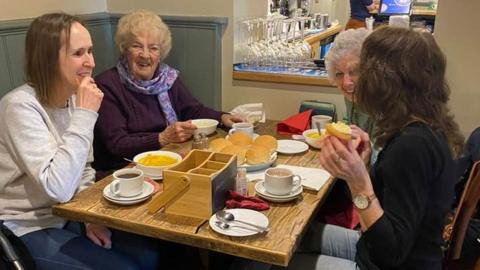 Four women enjoying a cup of tea and chatting at The Rising Sun