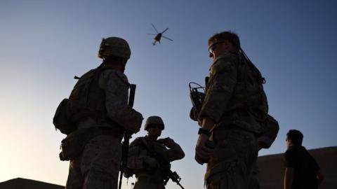 US Marines and Afghan commandos stand together as an Afghan Air Force helicopter flies past during a combat training exercise at Shorab Military Camp in Lashkar Gah in Helmand province, 27 August 2017