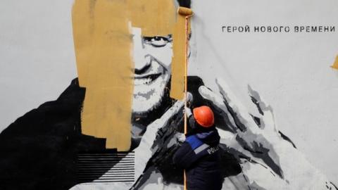 A worker paints over a graffiti depicting jailed Russian opposition politician Alexei Navalny in Saint Petersburg