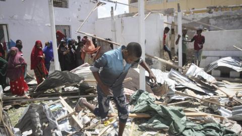 People gather around rubble at the scene of an explosion that hit Somalia's capital Mogadishu
