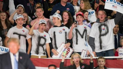 Supporters wear t-shirts spelling out "Trump" at an iowa rally.