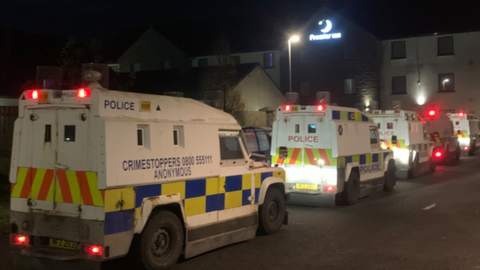 Five police Land Rovers parked in front of a Premier Inn