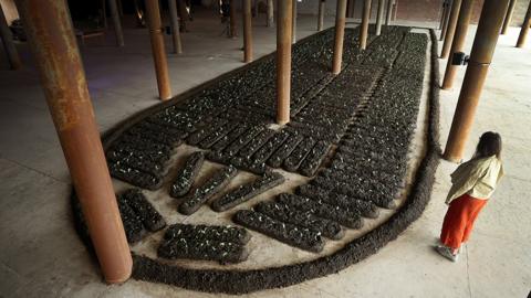 A woman looks at "Chorus of Soil' a work by Italian artist Binta Diaw which is a large scale reproduction of the shape of the slave ship 'Brooks' constructed of seeds and soil